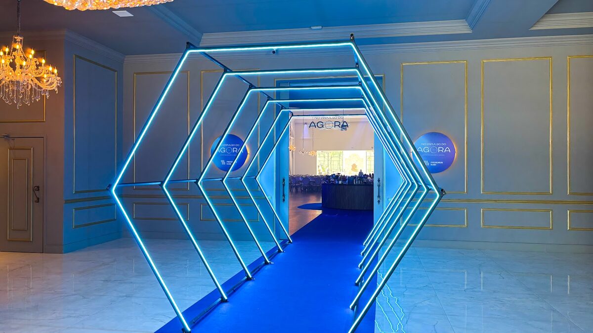 Túnel cenográfico com iluminação azul e hexagonal criando atmosfera envolvente em evento corporativo
