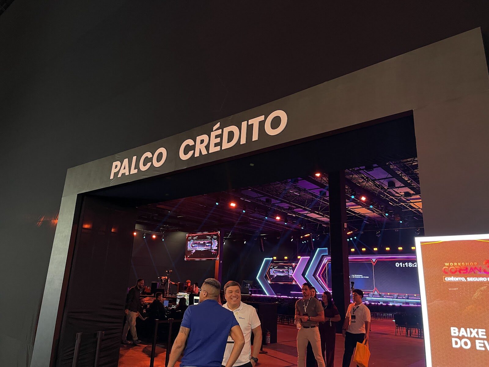 Entrada de evento com iluminação cênica colorida e visitantes circulando