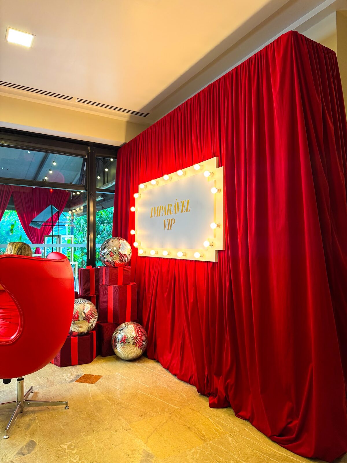 Camarim VIP com cortina de veludo, letreiro luminoso e esferas espelhadas em festa