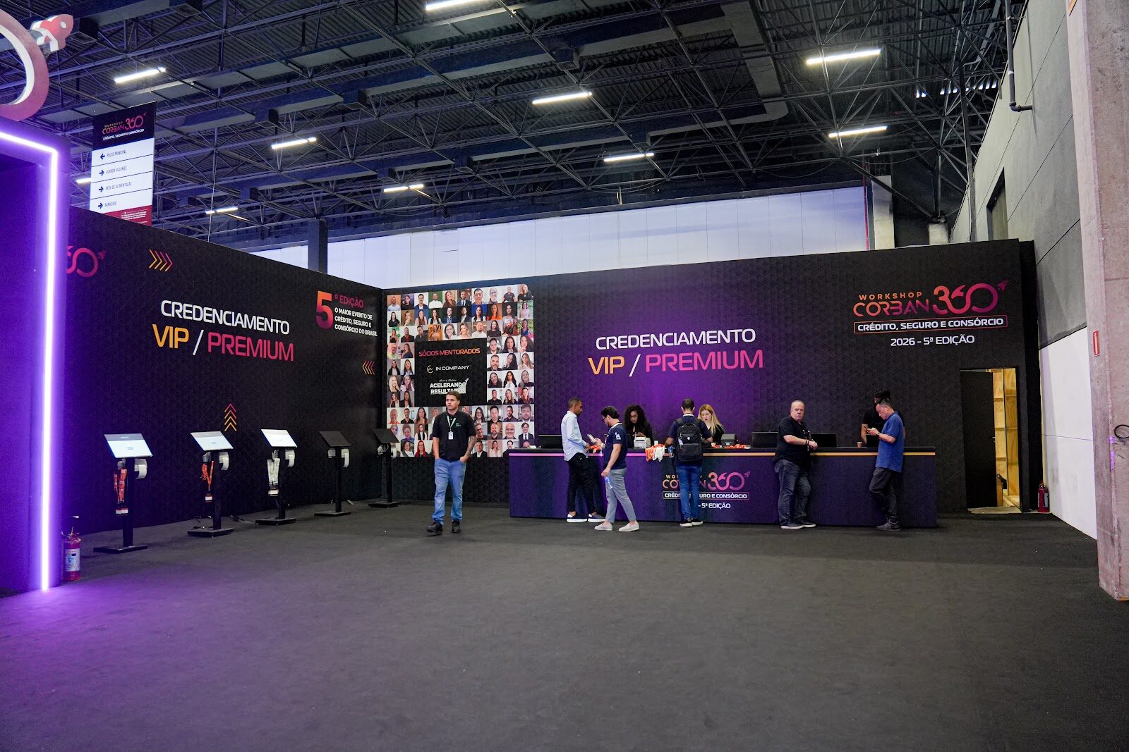 Balcão de credenciamento VIP com painel iluminado e totens digitais