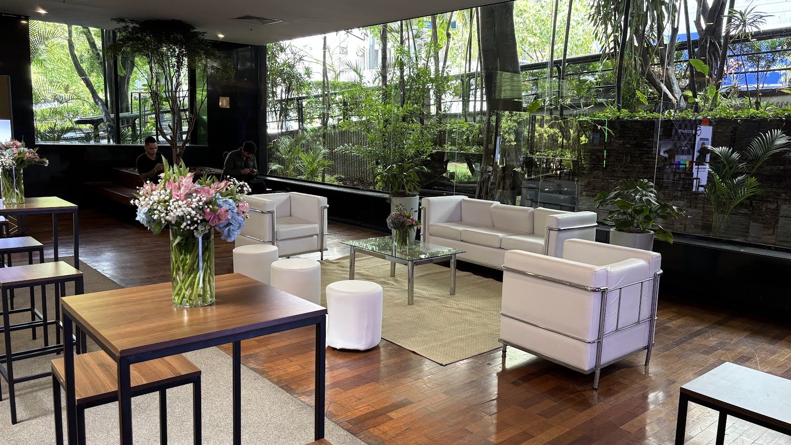 Lounge com sofás brancos e arranjos florais em área cenográfica de evento social