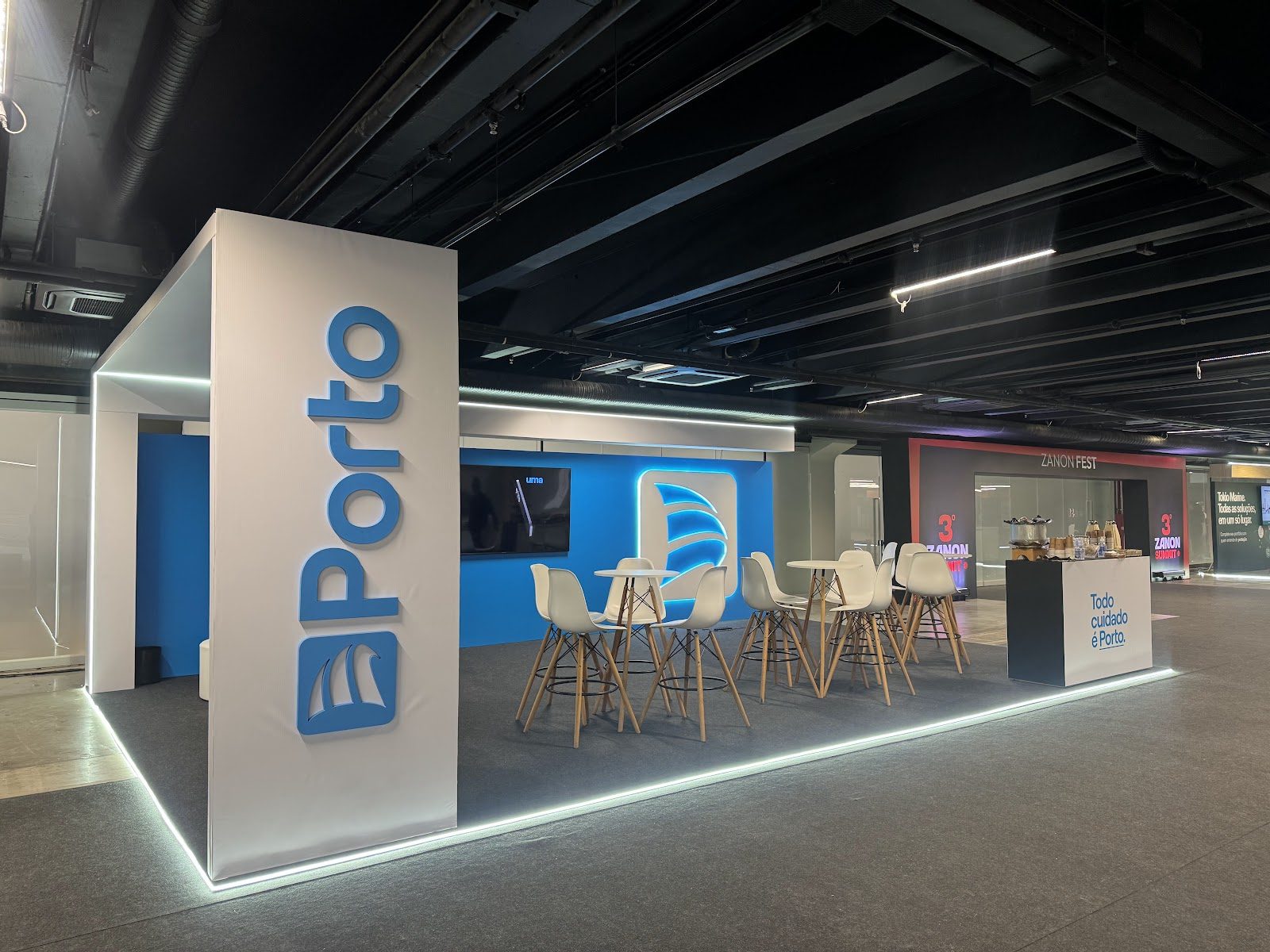Painel azul iluminado com logotipo em relevo em stand de feira corporativa