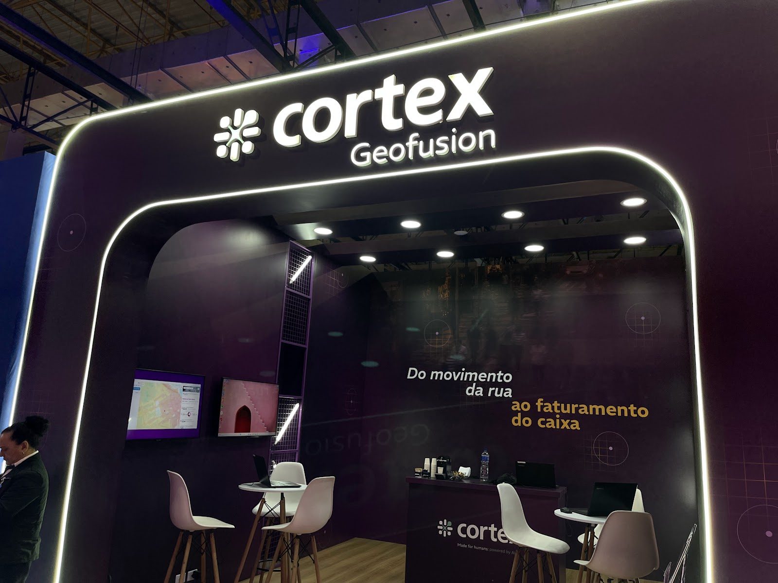 Stand com arco iluminado e painéis de LED em pavilhão de feira de negócios