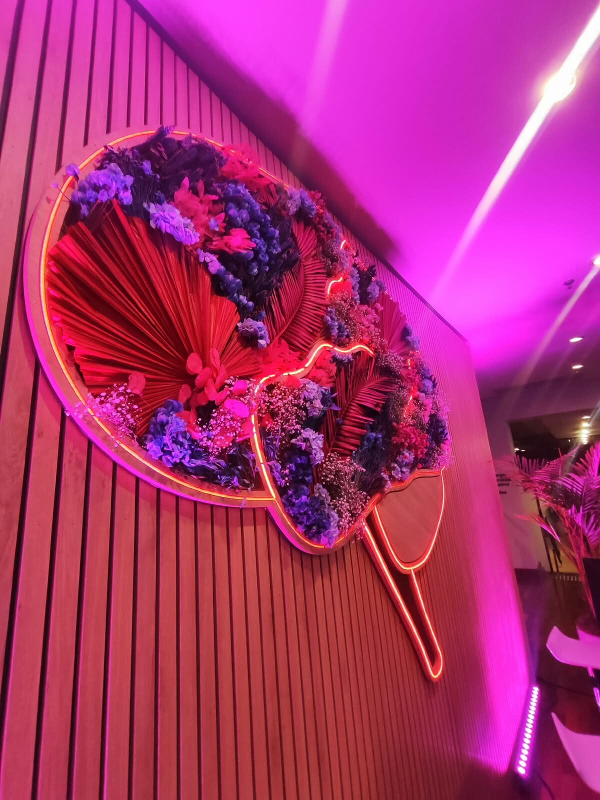 Detalhe de escultura em botânicos preservados com iluminação neon colorida, integrada à identidade de uma ativação de marca