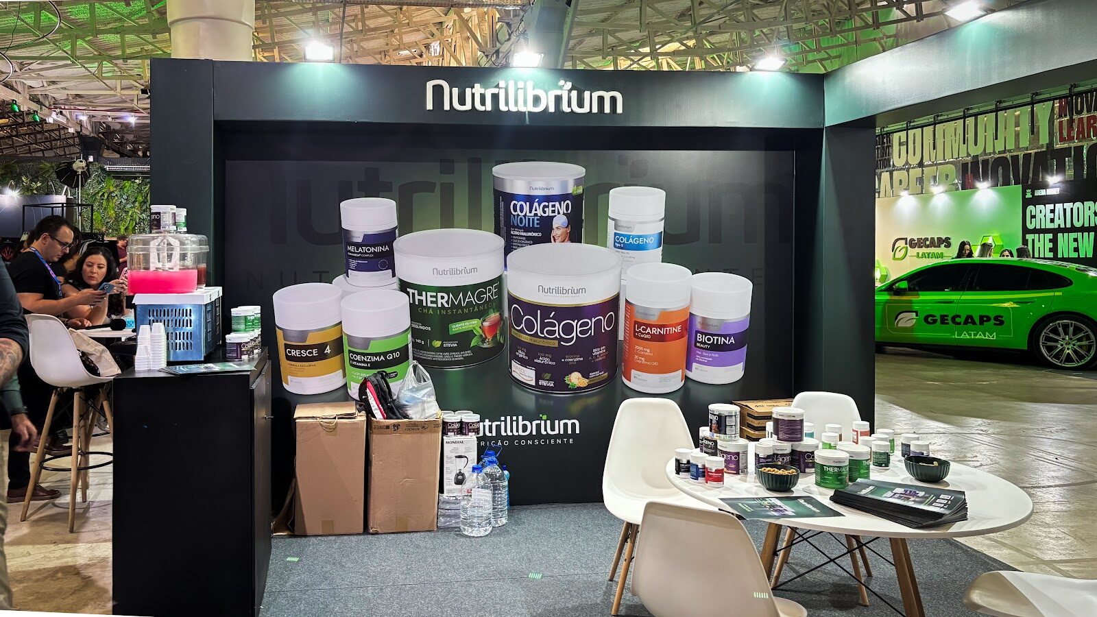 Stand de feira de suplementos com produtos expostos, bancada lateral e mesa para degustação