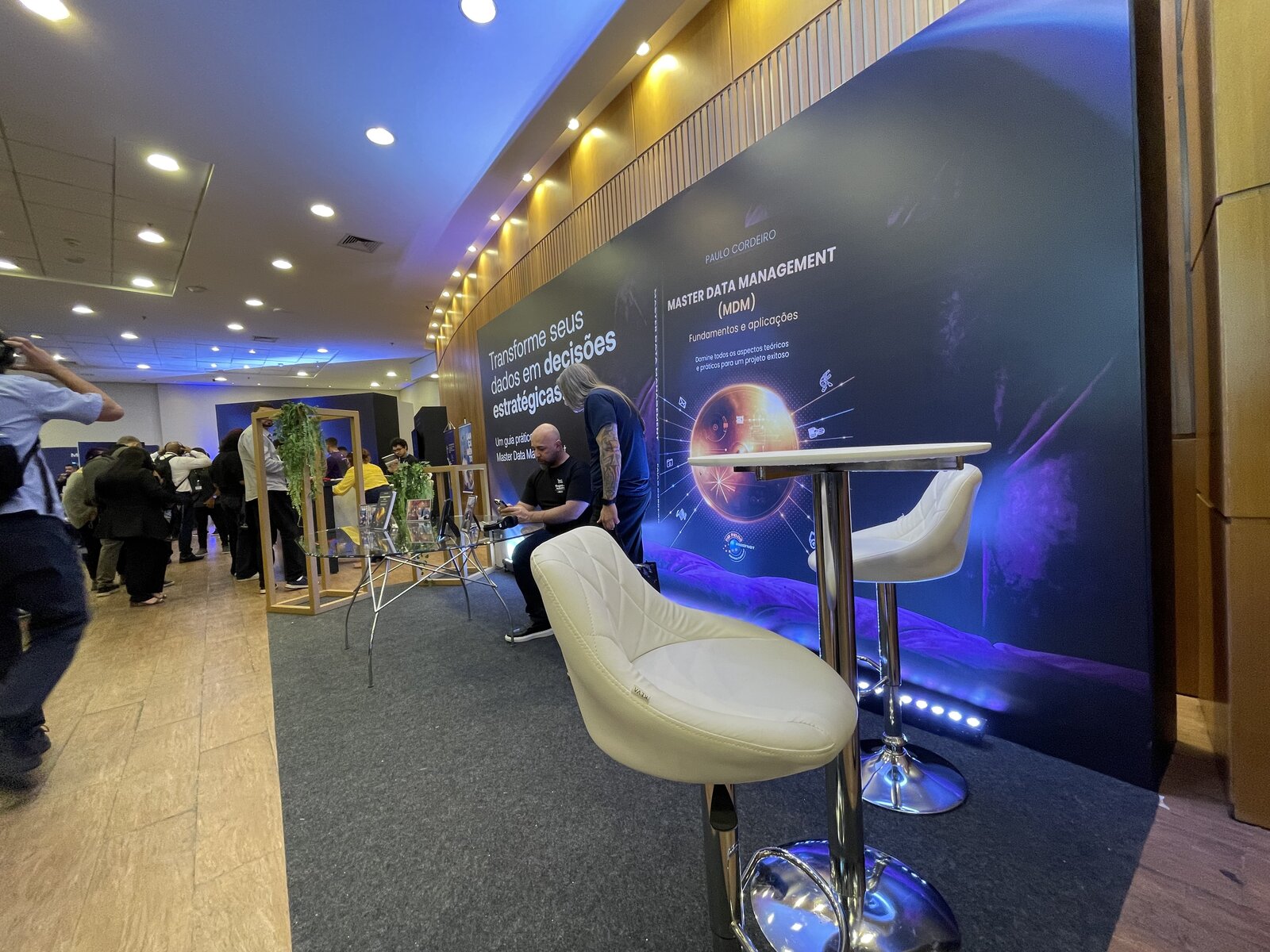 Espaço de atendimento e área de estar do evento Amigos do Cadastro, com mesas altas e banquetas, produzido pela Atom Cenografia
