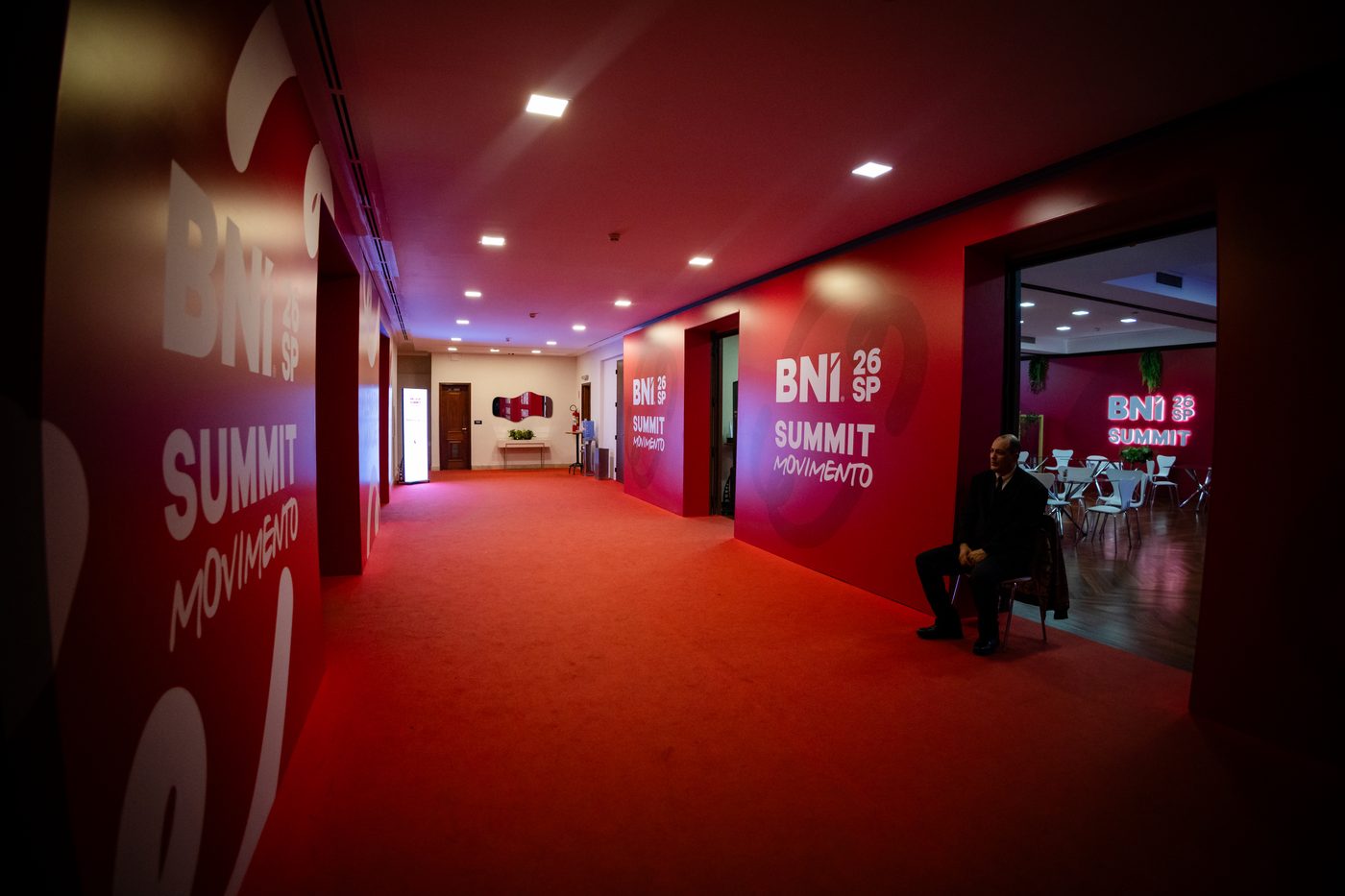 Corredor de acesso do BNI Summit 26 SP com padrão gráfico ondulado vermelho e branco do conceito Movimento