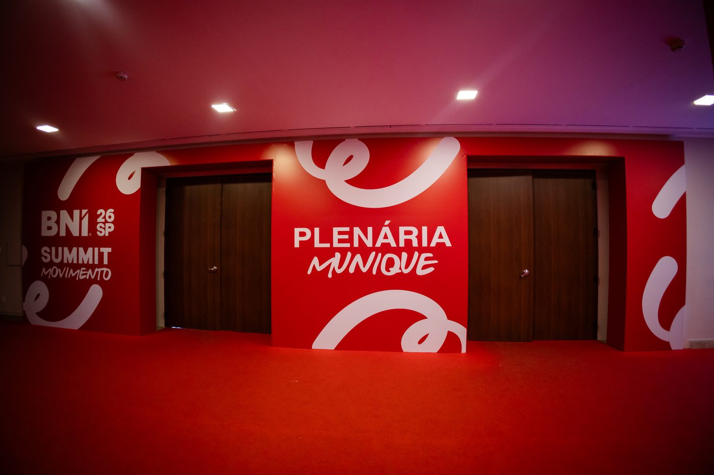 Pórtico de acesso à Plenária Munique do BNI Summit 26 SP, com padrão gráfico em curva aplicado nas portas