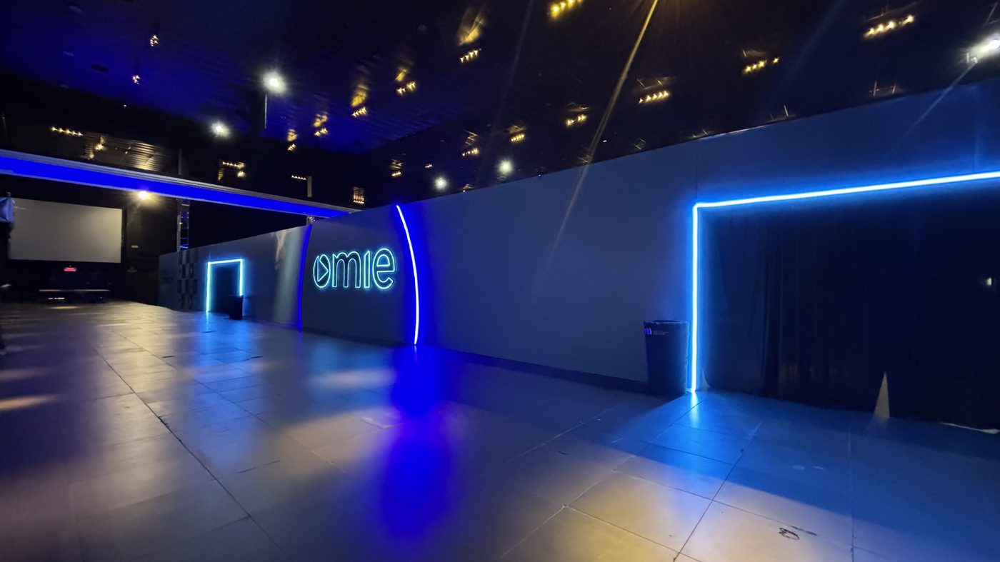 Abertura de 4 metros do pórtico contornada por neon flex, cenografia Atom para a Omie