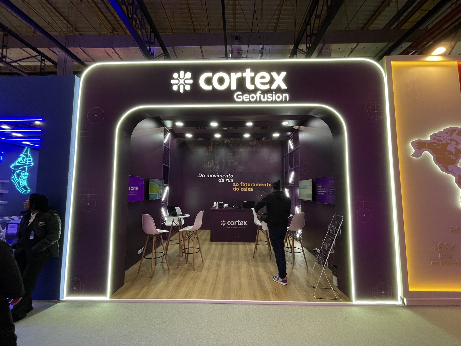 Fachada do stand da Cortex Geofusion na ABF Franchising Expo 2026, com testeira em arco iluminada e letreiro retroiluminado, montado pela Atom Cenografia